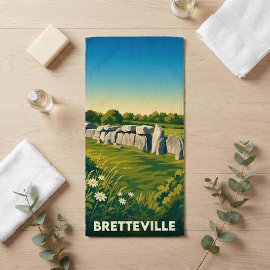 Serviette de bain souvenir de la ville de Bretteville avec une illustration stylisée de dolmens dans un paysage verdoyant.