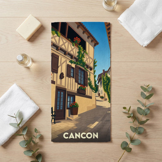 Serviette de bain souvenir de la ville de Cancon illustrée d'une ruelle médiévale pittoresque.