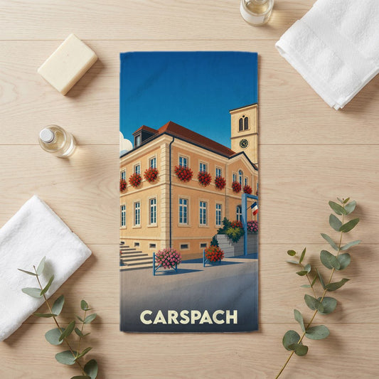Serviette de bain souvenir de la ville de Carspach avec une illustration stylisée de sa mairie fleurie.