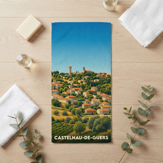 Serviette de bain souvenir de la ville de Castelnau-de-Guers avec une illustration stylisée d'un village perché.