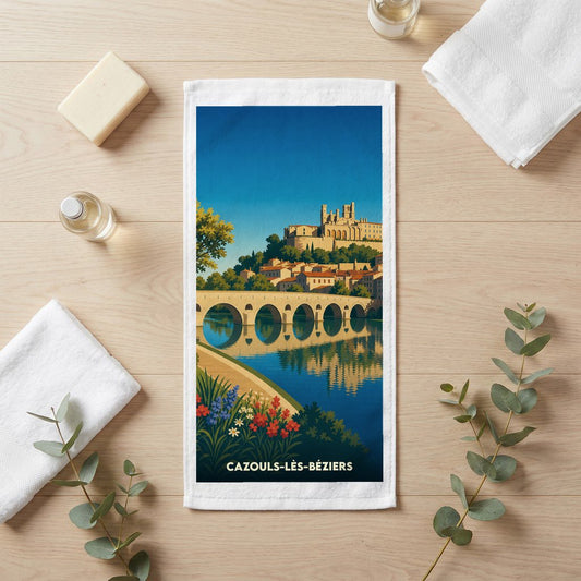 Serviette de bain souvenir de la ville de Cazouls-lès-Béziers avec une illustration stylisée d'un pont et d'un château.