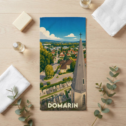 Serviette de bain souvenir de la ville de Domarin ornée d'une illustration stylisée de son clocher et de ses paysages.