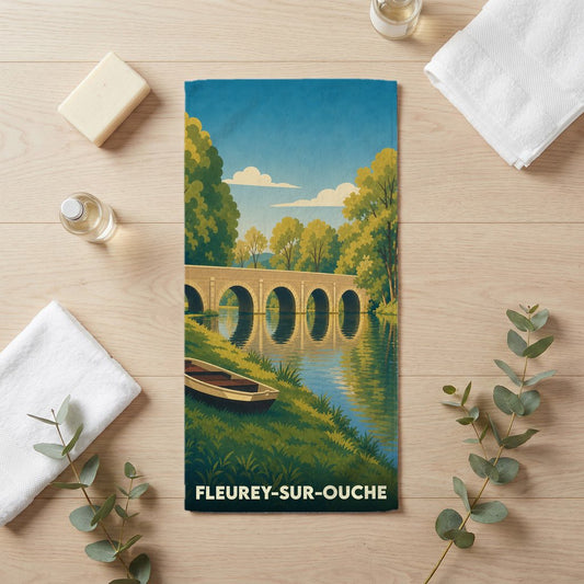 Serviette de bain souvenir de Fleurey-sur-Ouche illustrée d'un paysage de rivière et d'un pont de pierre.