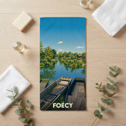 Serviette de bain souvenir de la ville de Foëcy avec une illustration stylisée de barques sur un canal.