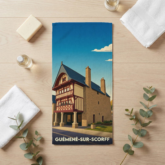 Serviette de bain souvenir de la ville de Guémené-sur-Scorff avec une illustration stylisée d'une maison à colombages.