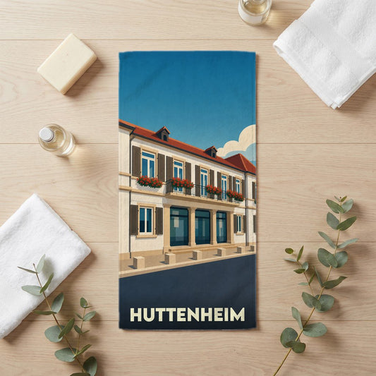 Serviette de bain souvenir de la ville de Huttenheim avec une illustration stylisée d'un bâtiment à colombages.