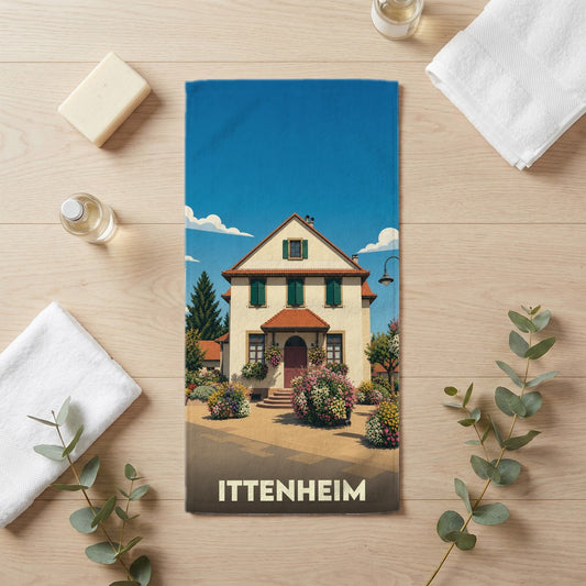 Serviette de bain souvenir de la ville d'Ittenheim avec une illustration stylisée d'une maison alsacienne fleurie.