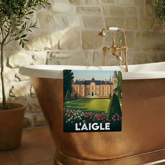 Serviette de bain souvenir de la ville de L'Aigle avec une illustration stylisée d'un château.