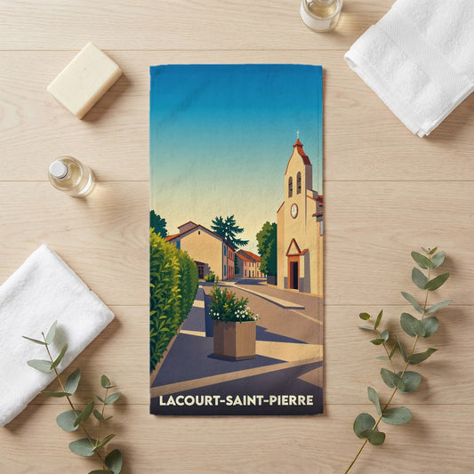 Serviette de bain souvenir de la ville de Lacourt-Saint-Pierre avec une illustration stylisée d'une rue ensoleillée et de son église.