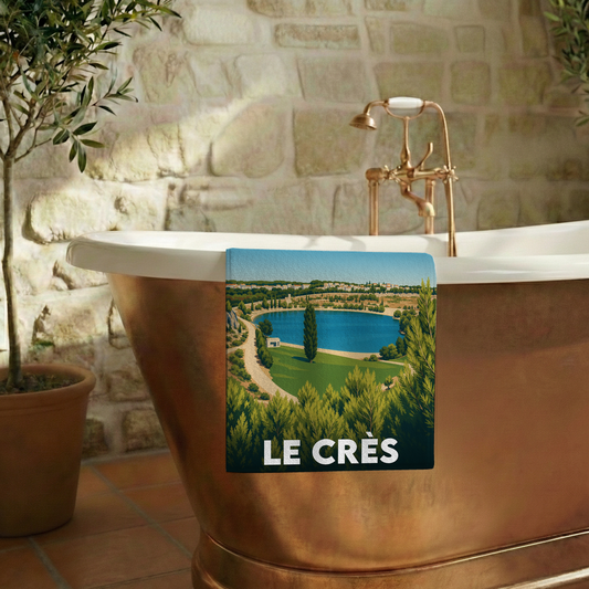 Serviette de bain souvenir de la ville de Le Crès avec une illustration stylisée d'un lac bordé de verdure.