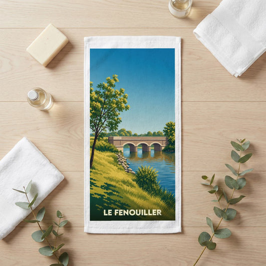 Serviette de bain souvenir de la ville de Le Fenouiller avec une illustration stylisée d'un pont sur une rivière.