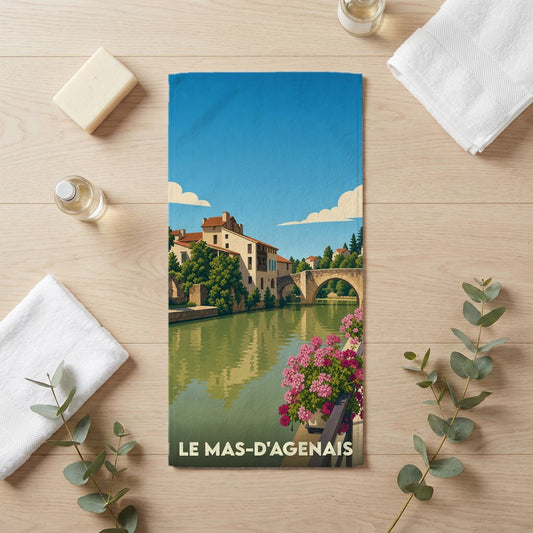 Serviette de bain souvenir de la ville du Mas-d'Agenais avec une illustration stylisée d'un paysage fluvial.