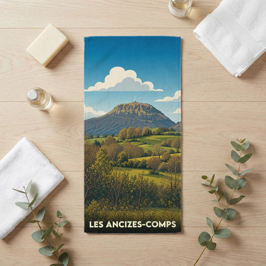 Serviette de bain souvenir de la ville des Ancizes-Comps avec une illustration stylisée de paysages vallonnés.