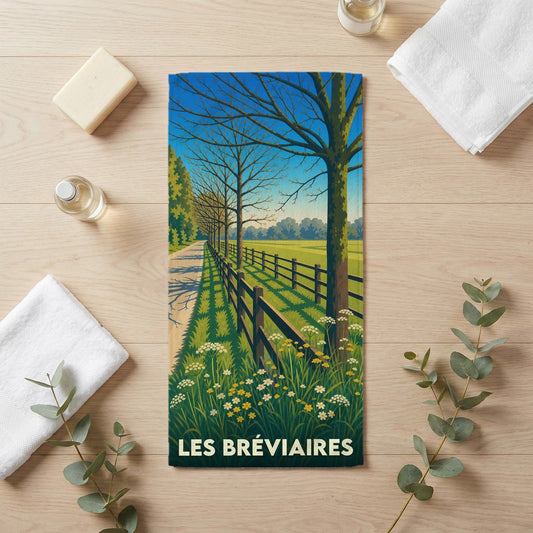 Serviette de bain souvenir de la ville de Les Bréviaires avec une illustration stylisée d'un paysage champêtre.