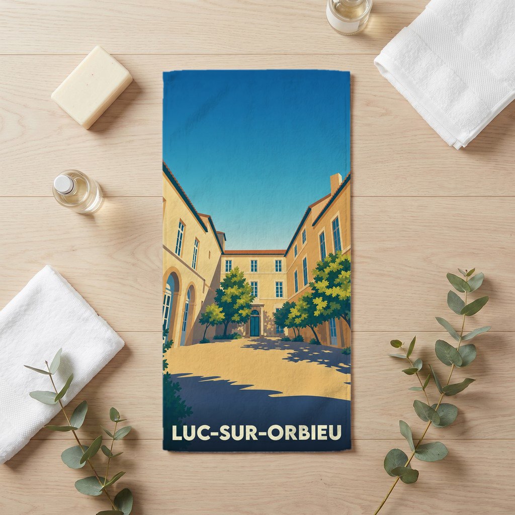 Serviette de bain souvenir de la ville de Luc-sur-Orbieu avec une illustration stylisée d'une place ensoleillée.
