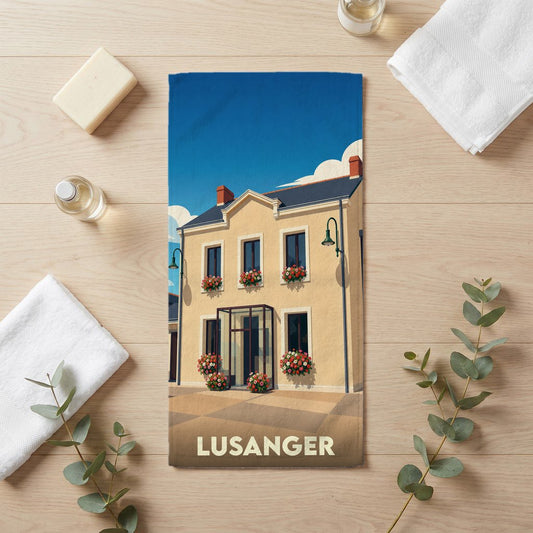 Serviette de bain souvenir de la ville de Lusanger avec une illustration stylisée d'une maison fleurie.