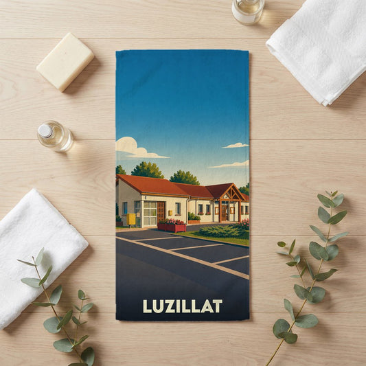 Serviette de bain souvenir de la ville de Luzillat avec une illustration stylisée d'un bâtiment communal.