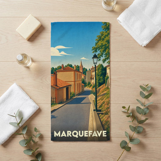 Serviette de bain souvenir de la ville de Marquefave avec une illustration stylisée d'une rue ensoleillée.