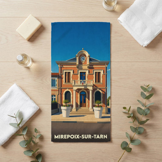 Serviette de bain souvenir de Mirepoix-sur-Tarn ornée d'une illustration stylisée de la mairie sous un ciel bleu.