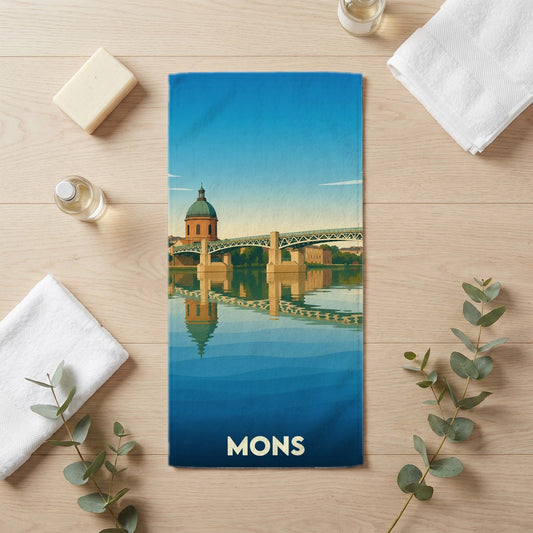 Serviette de bain souvenir de la ville de Mons avec une illustration stylisée d'un dôme et d'un pont se reflétant dans l'eau.