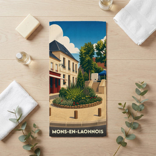 Serviette de bain souvenir de Mons-en-Laonnois illustrée d'une scène de village stylisée et colorée.