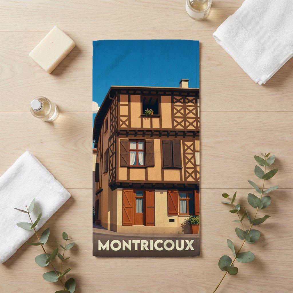 Serviette de bain souvenir de la ville de Montricoux avec une illustration stylisée d'une maison à colombages.