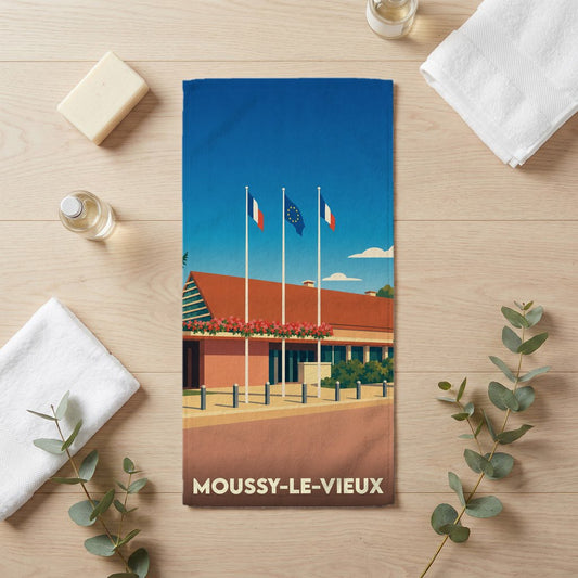 Serviette de bain souvenir de la ville de Moussy-le-Vieux avec une illustration stylisée d'un bâtiment officiel et de drapeaux.