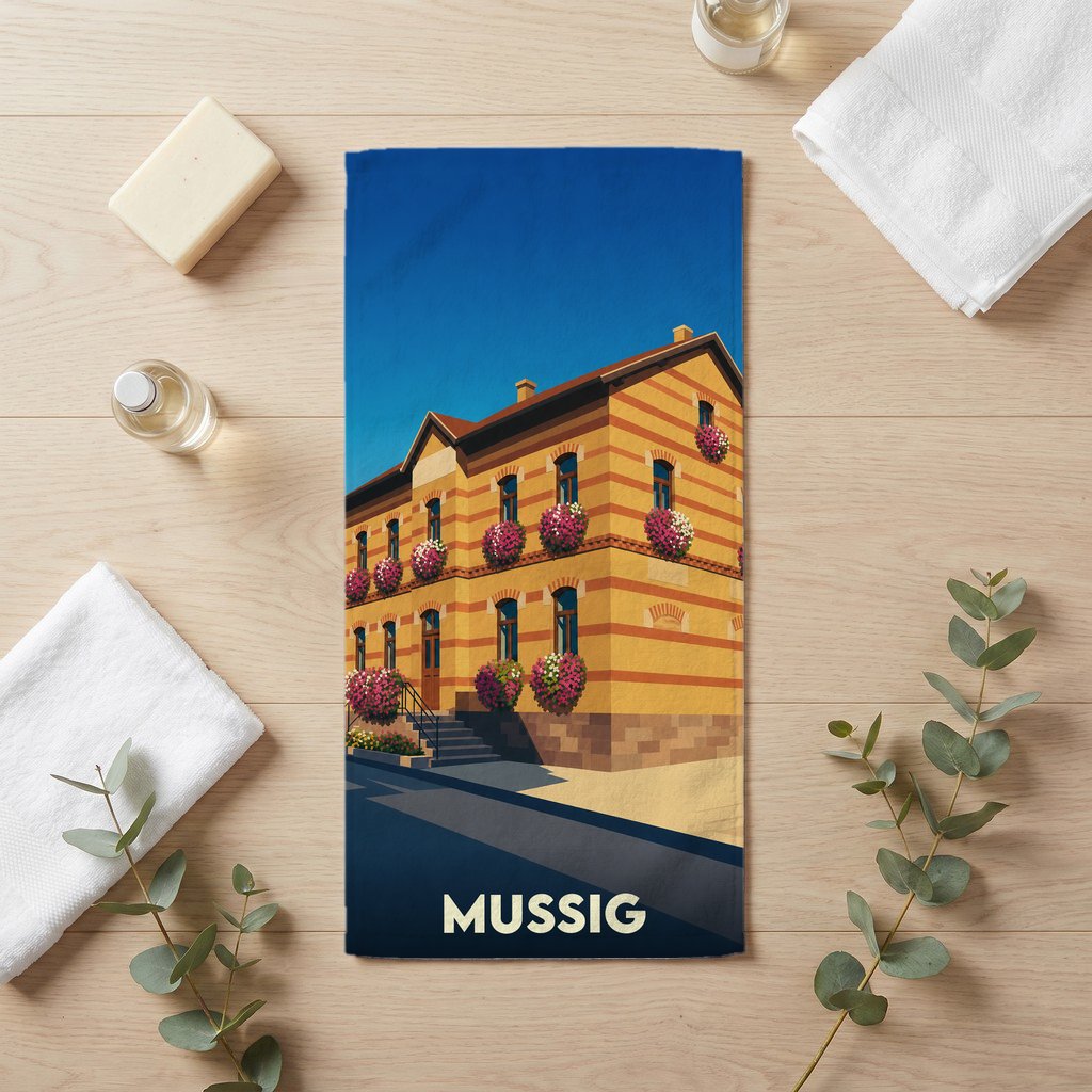 Serviette de bain souvenir de la ville de Mussig illustrée d'un bâtiment typique alsacien fleuri.