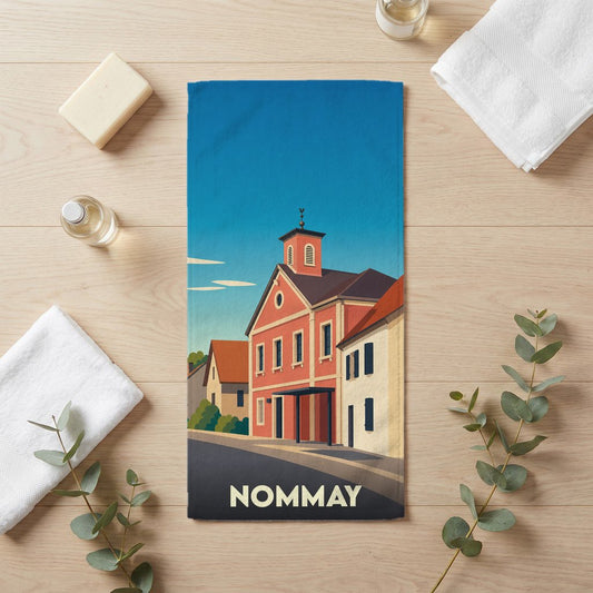Serviette de bain souvenir de la ville de Nommay illustrée par un dessin stylisé de ses bâtiments colorés.