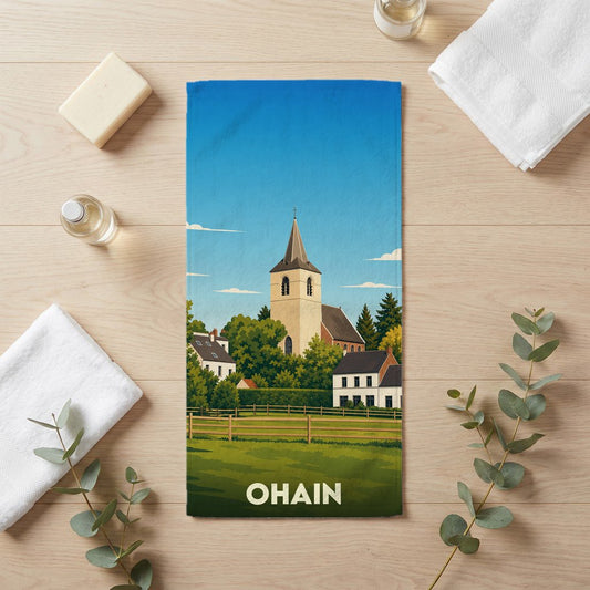 Serviette de bain souvenir de la ville d'Ohain illustrée d'un paysage de village pittoresque avec son église.