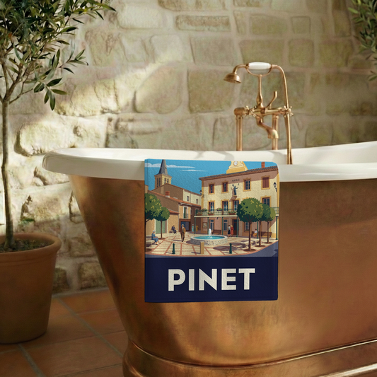 Serviette de bain souvenir de la ville de Pinet avec une illustration stylisée de sa place principale.