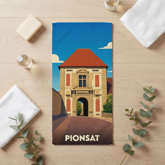 Serviette de bain souvenir de la ville de Pionsat avec une illustration stylisée d'un bâtiment historique.