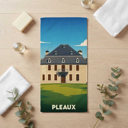 Serviette de bain souvenir de la ville de Pleaux avec une illustration stylisée d'une demeure traditionnelle.