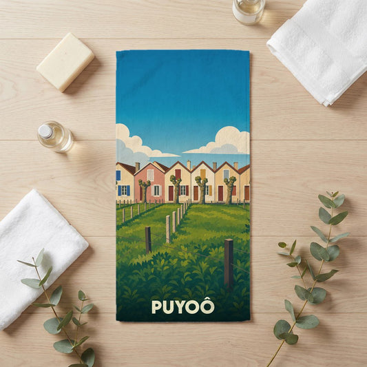 Serviette de bain souvenir de la ville de Puyoô avec une illustration stylisée de maisons colorées et de verdure.