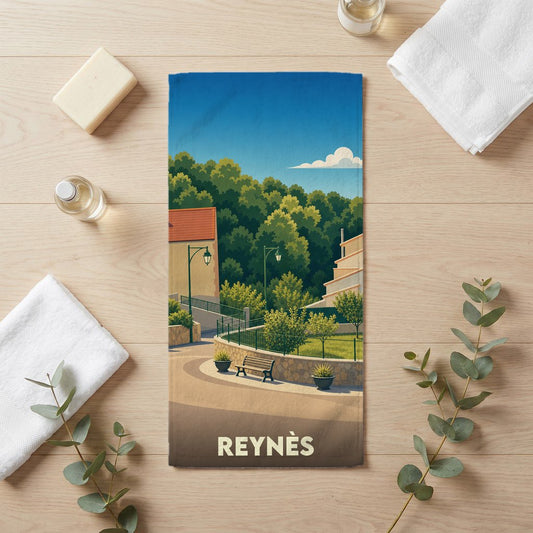 Serviette de bain souvenir de la ville de Reynès avec une illustration stylisée de ses paysages.