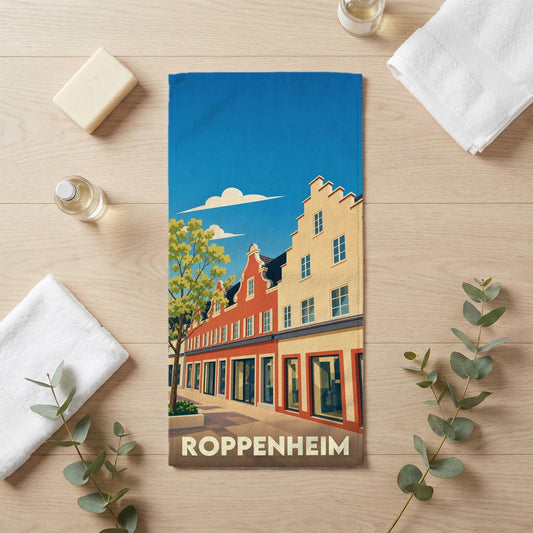 Serviette de bain souvenir de la ville de Roppenheim avec une illustration stylisée de bâtiments traditionnels alsaciens.
