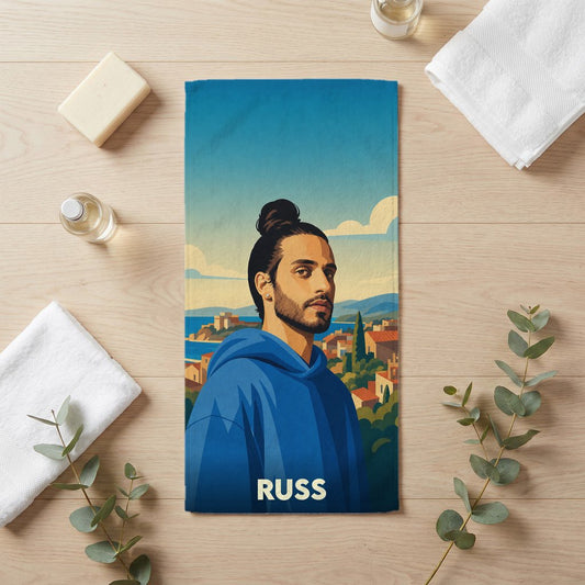 Serviette de bain souvenir de la ville de Russ avec une illustration stylisée d'un homme devant un paysage méditerranéen.
