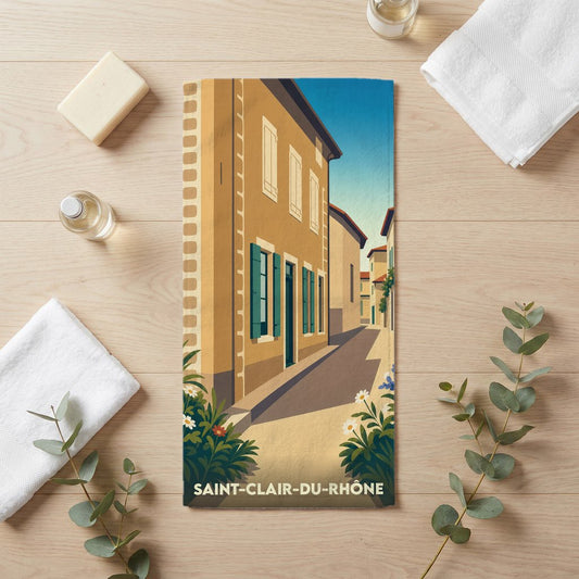 Serviette de bain souvenir de Saint-Clair-du-Rhône avec une illustration stylisée d'une rue ensoleillée.