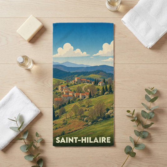 Serviette de bain souvenir de la ville de Saint-Hilaire avec une illustration de paysage vallonné.