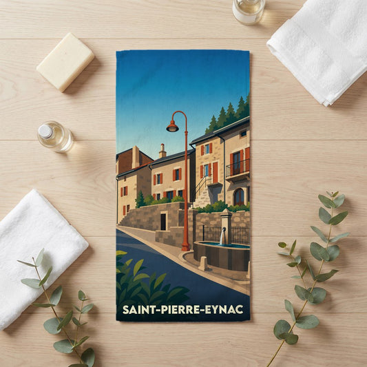 Serviette de bain souvenir de Saint-Pierre-Eynac illustrée d'un paysage urbain stylisé avec fontaine et maisons anciennes.