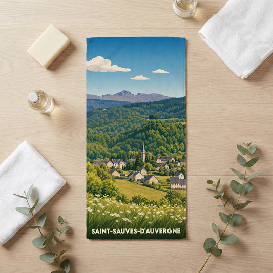 Serviette de bain souvenir de Saint-Sauves-d'Auvergne avec une illustration stylisée du village et des montagnes.