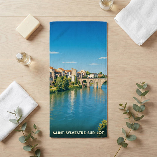 Serviette de bain souvenir de Saint-Sylvestre-sur-Lot illustrant un pont enjambant une rivière.