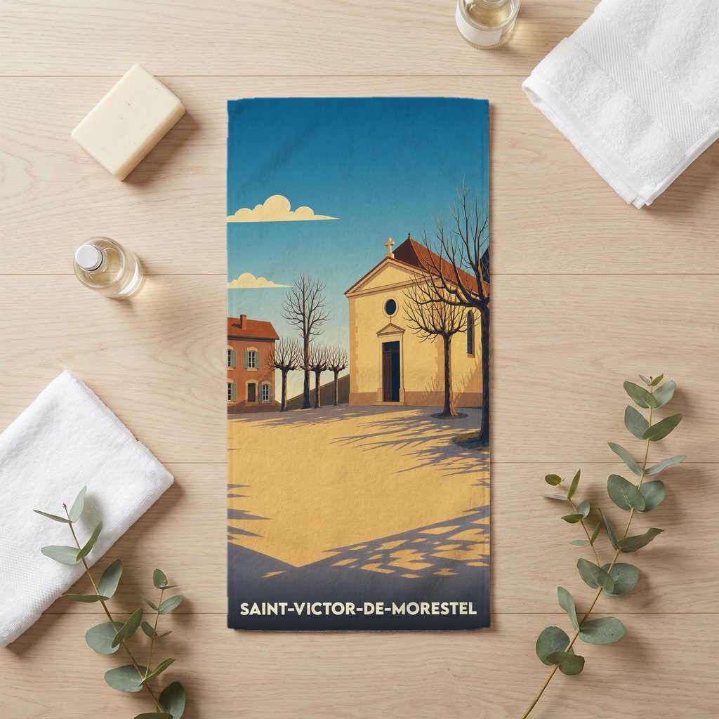 Serviette de bain souvenir de Saint-Victor-de-Morestel illustrée d'un dessin stylisé de son église sous un ciel bleu.