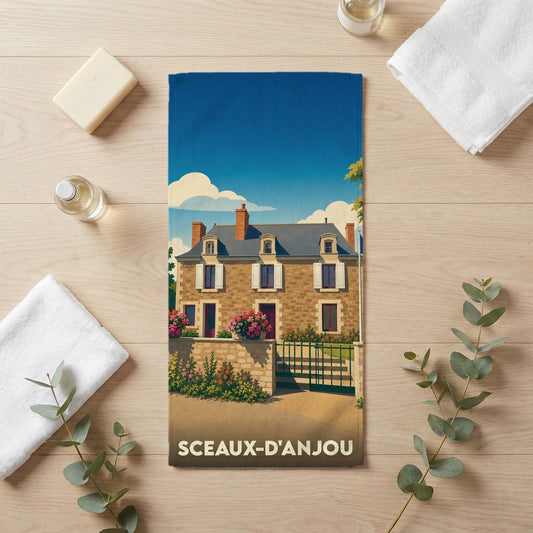 Serviette de bain souvenir de la ville de Sceaux-d'Anjou avec une illustration stylisée d'une maison traditionnelle.