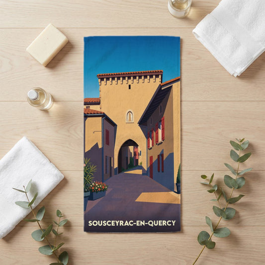 Serviette de bain souvenir de Sousceyrac-en-Quercy avec une illustration stylisée de ses rues historiques.