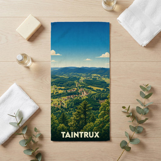 Serviette de bain souvenir de la ville de Taintrux avec une illustration de paysage vallonné.