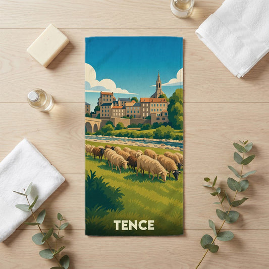 Serviette de bain souvenir de la ville de Tence illustrée de moutons et d'un paysage urbain stylisé.