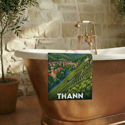 Serviette de bain souvenir de la ville de Thann avec une illustration stylisée d'un paysage de vignobles.
