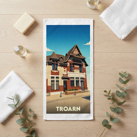 Serviette de bain souvenir de la ville de Troarn avec une illustration stylisée d'un bâtiment typique.