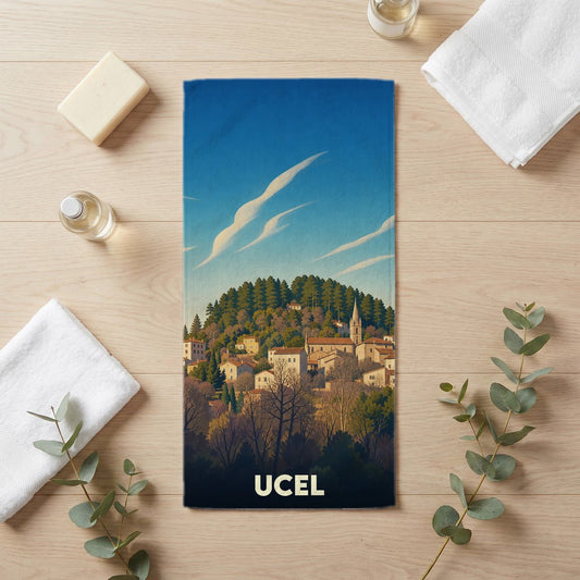 Serviette de bain souvenir de la ville de Ucel avec une illustration stylisée d'un village perché.
